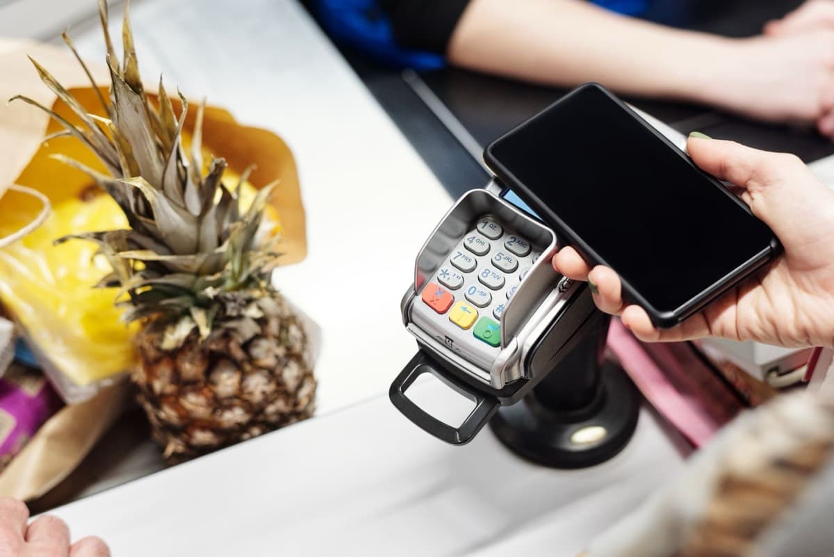 A shopper paying at a store counter with a smartphone